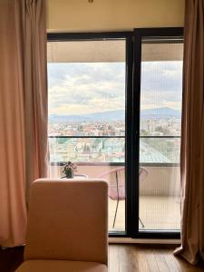 um quarto com uma cadeira e uma grande janela em The Golden Sunset flat em Skopje