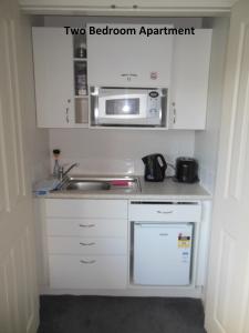 a kitchen with a sink and a microwave at Silverdale Garden Stay in Orewa