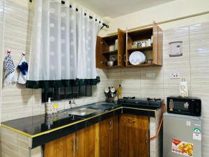 een kleine keuken met een wastafel en een koelkast bij The Cosy Corner in Kisii