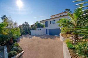 a house with a driveway and palm trees at Villa L, Vue mer, plage 10 min à pied in Sainte-Maxime
