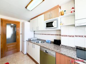 eine Küche mit weißen Schränken und einem Waschbecken in der Unterkunft Joya Mediterránea in Benicàssim