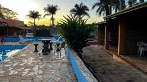 a patio with a palm tree next to a pool at Pousada das Cores in Olímpia