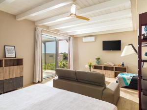 ein Schlafzimmer mit einem Bett, einer Couch und einem Fernseher in der Unterkunft Agua Green Resort in Reitani