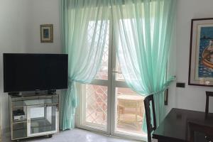 a living room with a television and a sliding glass door at Casa MaLù in Ladispoli