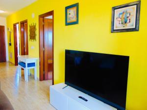 sala de estar con TV de pantalla plana en una pared amarilla en Casita La Caleta Fuerteventura, en Parque Holandes