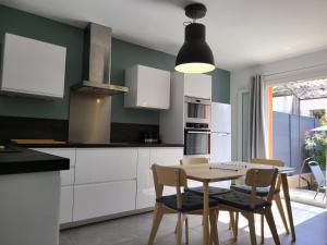 a kitchen with white cabinets and a table and chairs at Le temps d'une pause in Villes-sur-Auzon