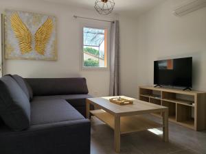 a living room with a couch and a tv and a table at Le temps d'une pause in Villes-sur-Auzon