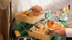 a person holding a plate of bread and baskets of bread at Hotel Alpha Paris Eiffel by Patrick Hayat in Boulogne-Billancourt