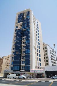 een groot gebouw met auto's geparkeerd voor het bij Couples Room tv fridge close to metro in Dubai