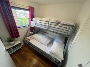 three bunk beds in a room with a window at 159, Two bed Chalet on Sunbeach Holiday Park - Sleeps 5, pet friendly - Onsite entertainment, SWIMMING PASSES INCLUDED - plus WiFi, bed linen and towels included - only 300m from the beach! in Scratby +21 photos