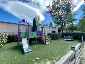 une cour avec une aire de jeux dotée d'un toboggan et d'équipements de jeux dans l'établissement Les jardins de Tivoli, au Grau-du-Roi