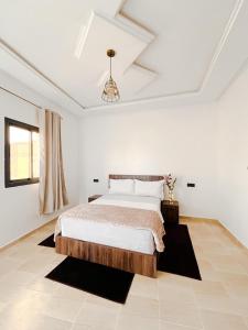 a white bedroom with a bed and a chandelier at Hotel Ahmed Ali in Dakhla