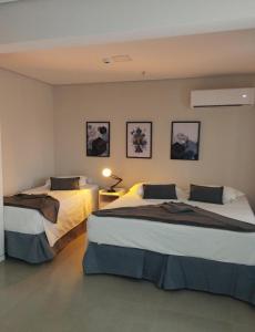 ein Hotelzimmer mit 2 Betten und einer Lampe in der Unterkunft Diamond Hotéis e Flats in São Lourenço