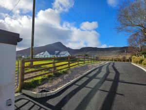 a fence on the side of a road with a house at Cosy 1 bedroom cottage, Ideal quiet getaway. in Creeslough