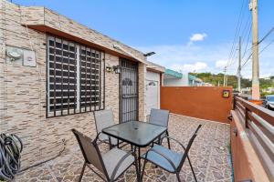 patio con mesa y sillas en el balcón en Lupa Guesthouse affordable family home, en Rincón