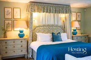 um quarto com uma cama com um cobertor azul e almofadas em Luxurious Vineyard Hideaway At Stanlake Park em Wokingham