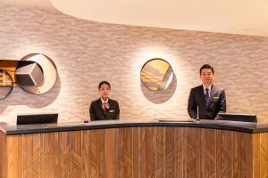 Dois homens de fato estão sentados numa secretária. em Nakajimaya Grand Hotel em Shizuoka