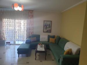 uma sala de estar com um sofá verde e uma mesa em Loren em Durrës
