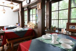 a dining room with two tables with red and white plates at Pension Belnina in Hakuba