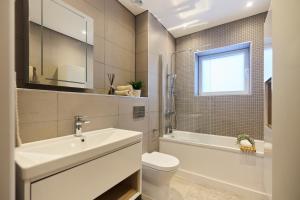 a bathroom with a sink and a toilet and a window at The Wembley Park Arms - Modern 2BDR Flat with Parking + Balcony in London