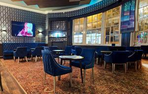 a bar with blue chairs and tables and a tv at Crown Hotel Stone in Stone