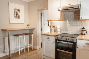 a kitchen with white cabinets and a stove at Cosy 2 bed cottage in charming village of Christleton - For up to 5 in Christleton