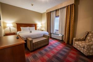 a hotel room with a bed and a chair at Christopher Inn and Suites in Chillicothe