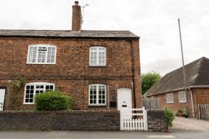 a brick house with a white fence and a white door at Cosy 2 bed cottage in charming village of Christleton - For up to 5 in Christleton