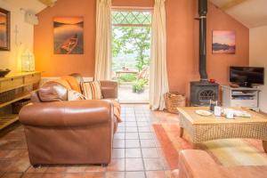 a living room with a leather couch and a fireplace at Thyme Lodge Drefach Felindre in Felindre