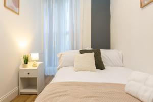 a bedroom with a white bed with a lamp and a window at Cozy 2BR Retreat | Prime Cardiff Location in Cardiff