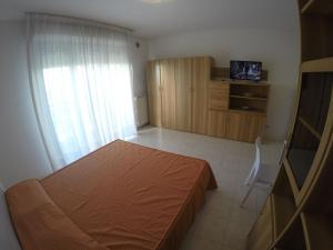 1 dormitorio con 1 cama, vestidor y TV en Monolocale Colombo - Agenzia Cocal, en Caorle