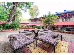 un patio con bancos, una mesa y un edificio en New Sun n S Resort Matheran, en Matheran