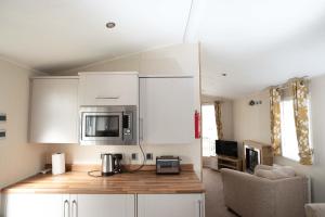 a kitchen with white cabinets and a microwave at Skegness Holidays in Skegness