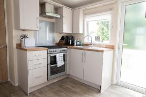 a kitchen with white cabinets and a sink and a stove at Skegness Holidays in Skegness
