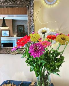 un jarrón de flores sentado en una mesa frente a un espejo en Hôtel Le Sénéchal, en Ars-en-Ré