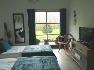 a bedroom with a bed and a television and a window at LA PAUSE in Surville