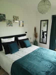 ein Schlafzimmer mit einem großen Bett mit blauen Kissen in der Unterkunft LA PAUSE in Surville