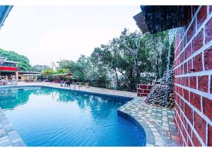 una gran piscina junto a un edificio de ladrillo en New Sun n S Resort Matheran, en Matheran
