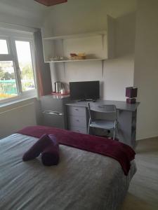 a bedroom with a bed with a desk and a computer at Welcoming Home Close to Transport Links in Thornton Heath