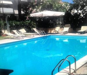 ein großer blauer Pool mit Stühlen und einem Sonnenschirm in der Unterkunft Nelly_house in Tortoreto Lido