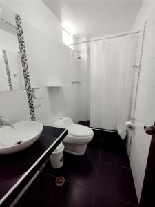 uma casa de banho branca com um lavatório e um WC em HOTEL FIORELLA PARACAS em Paracas