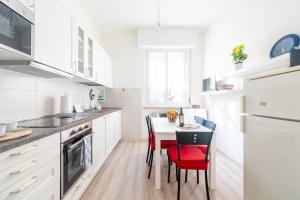 a kitchen with white cabinets and a table with red chairs at Oltretorrente Ospedale Apartment in Parma