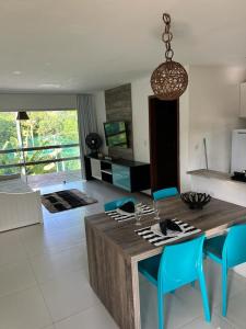 a kitchen with a wooden table and blue chairs at Apartamento Villas do Pratagy in Maceió