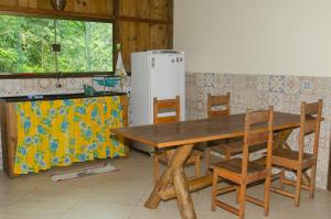 una mesa de madera y sillas en una cocina con nevera en Sitio recanto da natureza en Serra Grande