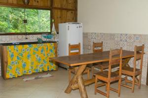 a wooden table and chairs in a kitchen with a refrigerator at Sitio recanto da natureza in Serra Grande