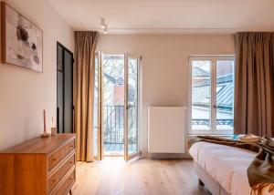 una camera con letto, cassettiera e finestre di Romantic getaway with terrace in Ghent a Gand