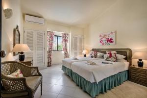 a bedroom with a large bed and a chair at Mng Elliott25 in Vale do Lobo +17 photos