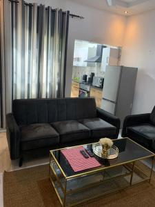 a living room with a black couch and a coffee table at The Retreat Apartments in Brusubi