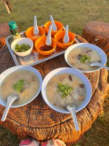 un tavolo con ciotole di zuppa e cucchiai sopra di ฟาร์มผัก Thank you a Ban Kom