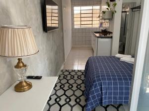 - une chambre avec un lit et une table avec une lampe dans l'établissement Residencial Sullivan - Florianópolis - Loft 03, à Florianópolis